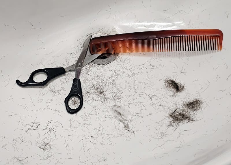 Comb, scissors and hair in the sink stock photo