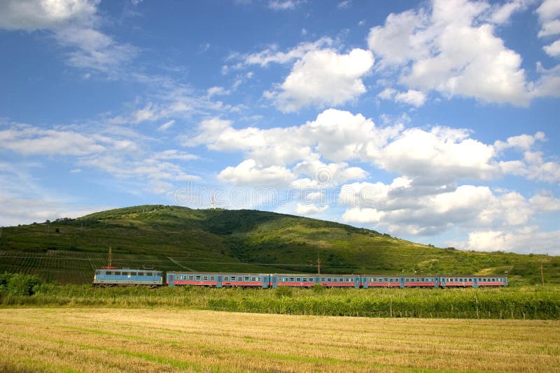 A passenger train under the Tokaj-hill, where the famous Hungarian Tokaji wine is producted. The train is hauled by a type V43 electric locomotive. A passenger train under the Tokaj-hill, where the famous Hungarian Tokaji wine is producted. The train is hauled by a type V43 electric locomotive.