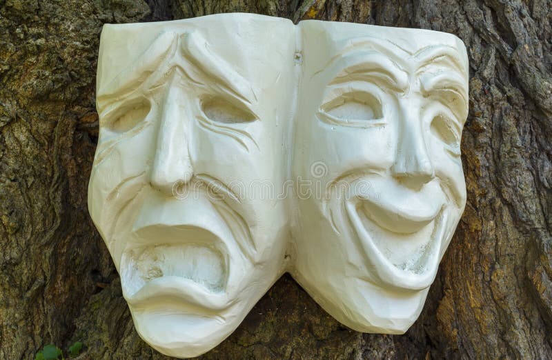 Theatrical mask of tragedy and comedy faces, carved out of wood on a tree trunk. Theatrical mask of tragedy and comedy faces, carved out of wood on a tree trunk.