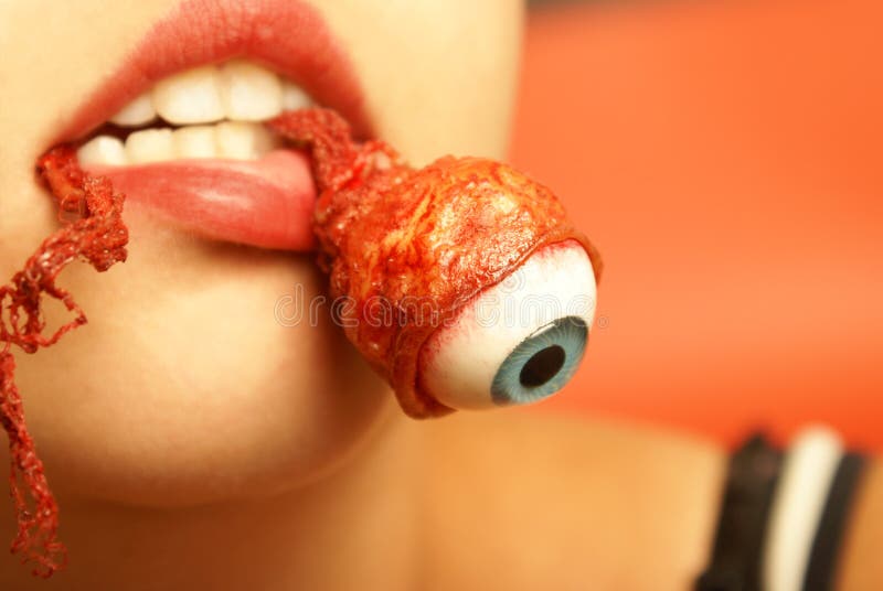 A woman takes a bite out of an eyeball. A woman takes a bite out of an eyeball.