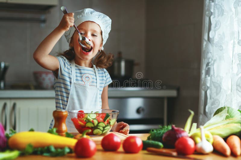 Comer saudável A menina feliz da criança prepara a salada vegetal no ki foto de stock Comer saudável A menina feliz da criança prepara a salada vegetal no ki foto de stock