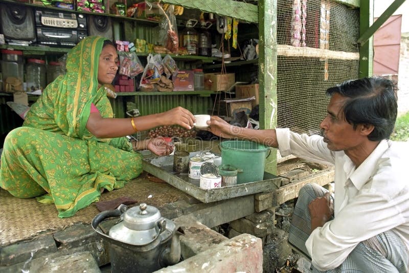 Bangladesh, capital, city Dhaka: in the district Mirpur is a saleswoman, entrepreneur, sitting in her shop on the ground and sells a cup of coffee to a male customer sitting in front of her stall. The woman is also vendor, street merchant of groceries on a very small scale. She is a small independent because she can make use of microcredit, a form of poverty alleviation. Bangladesh, capital, city Dhaka: in the district Mirpur is a saleswoman, entrepreneur, sitting in her shop on the ground and sells a cup of coffee to a male customer sitting in front of her stall. The woman is also vendor, street merchant of groceries on a very small scale. She is a small independent because she can make use of microcredit, a form of poverty alleviation.