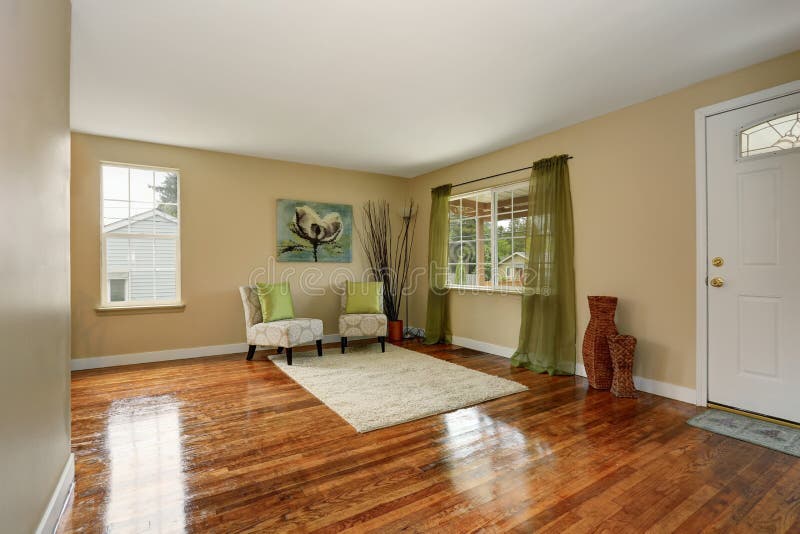 Cozy beige sitting room with shiny hardwood floor and green curtain. Furnished with two elegant antique armchairs with pillows and decorated with nice wicker vases. Cozy beige sitting room with shiny hardwood floor and green curtain. Furnished with two elegant antique armchairs with pillows and decorated with nice wicker vases.