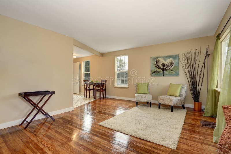 Cozy beige sitting room with shiny hardwood floor connected with dining area. Furnished with elegant antique armchairs and mahogany dining table set. Cozy beige sitting room with shiny hardwood floor connected with dining area. Furnished with elegant antique armchairs and mahogany dining table set.