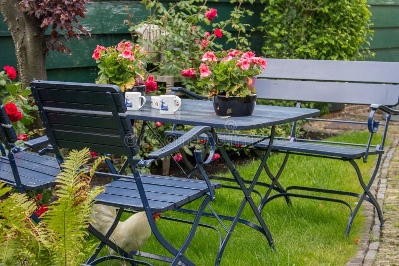 Comfortabele de zomerbinnenplaats met openluchtlijst en stoelen Terras met theelijst en witte kip onder stoel stock fotografie Comfortabele de zomerbinnenplaats met openluchtlijst en stoelen Terras met theelijst en witte kip onder stoel stock fotografie