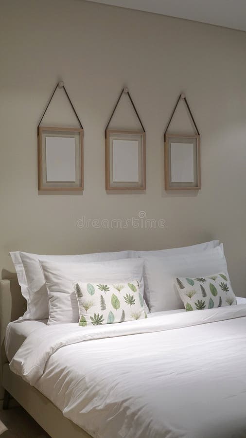 Comfortable Throw Cushion on the White Pillow S and White Bedsheet with Three Hanging Picture