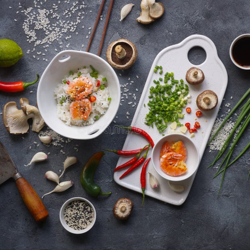 Comida asiática en un fondo oscuro, arroz del wok con los camarones y setas, durante la preparación fotos de archivo libres de regalías Comida asiática en un fondo oscuro, arroz del wok con los camarones y setas, durante la preparación fotos de archivo libres de regalías