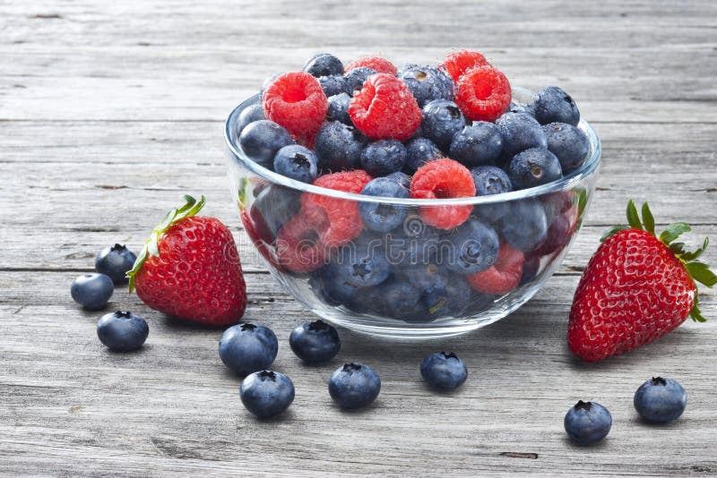 A bowl of fresh berries on a rustic wood background. A bowl of fresh berries on a rustic wood background