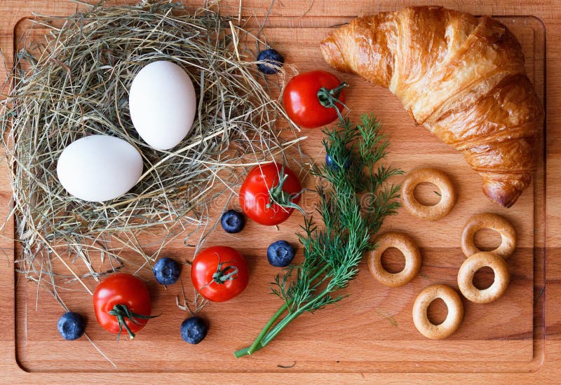Comida de la mañana con los huevos, el cruasán y los tomates imagen de archivo Comida de la mañana con los huevos, el cruasán y los tomates imagen de archivo