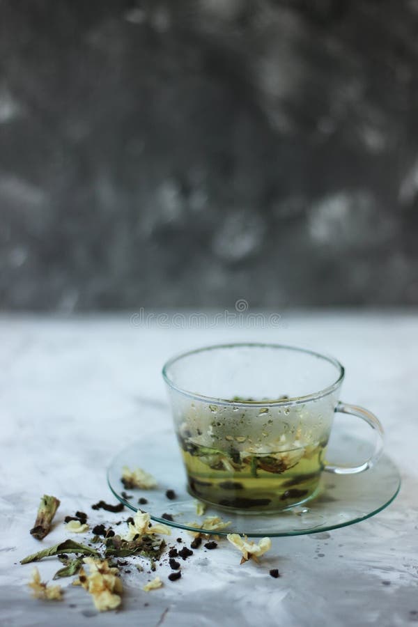 Comida del Detox y beber concepto healfhy de la forma de vida Taza de cristal de té verde con el jazmín en un fondo gris cierre imagen de archivo libre de regalías Comida del Detox y beber concepto healfhy de la forma de vida Taza de cristal de té verde con el jazmín en un fondo gris cierre imagen de archivo libre de regalías