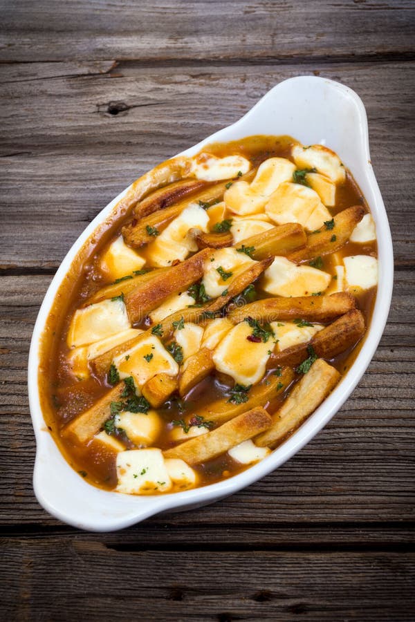 Comida deliciosa del poutine del restaurante en la tabla foto de archivo libre de regalías Comida deliciosa del poutine del restaurante en la tabla foto de archivo libre de regalías