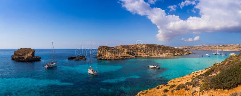 Comino, Malta - Panoramic skyline view of the famous and beautiful Blue Lagoon on the island of Comino with sailboats, traditional Luzzu boats and tourists enjoying the azure mediterranean sea water and sunshine