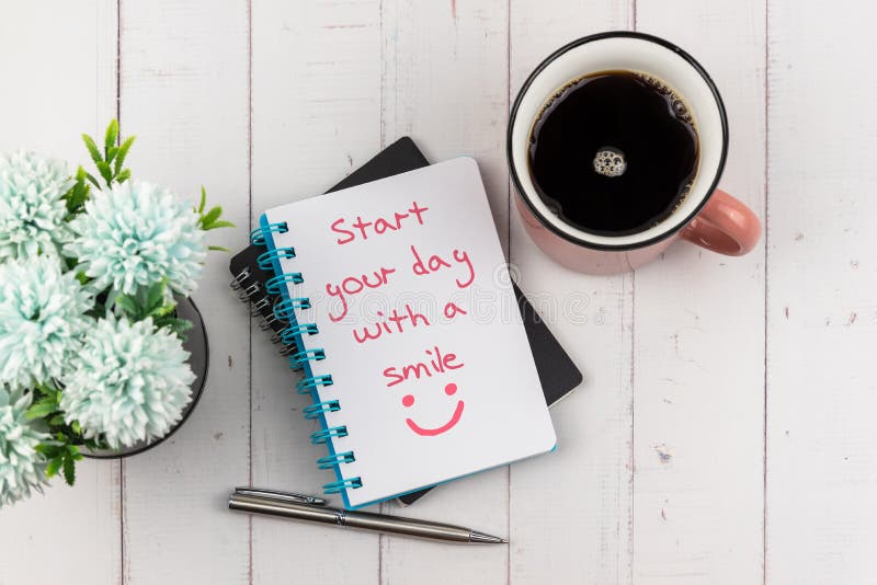 Commencez votre journée par un texte avec un sourire sur le carnet de notes avec une tasse de café et de fleur photo libre de droits