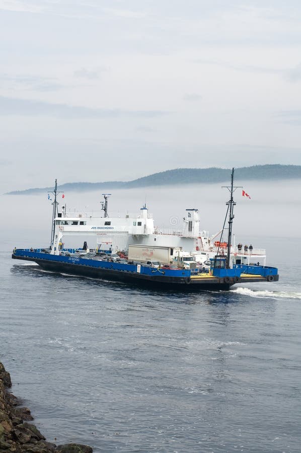 Commercial Ferry full of Tourists in Tadoussac Quebec with Mountains and Fog