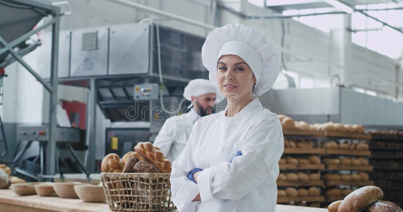 Commercieel gezicht van een geweldige vrouwelijke bakker die recht naar de camera kijkt en een leuke achtergrond glimlach op zijn