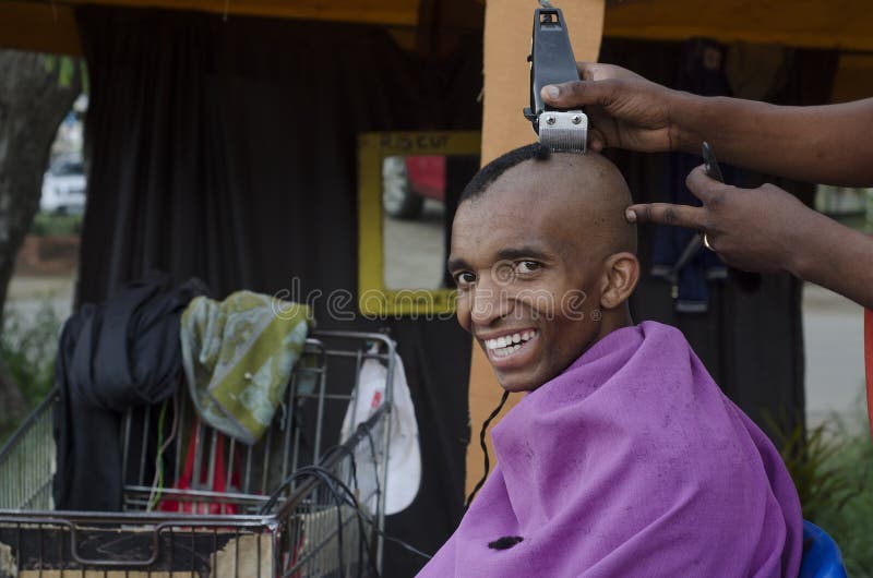 Commercio africano sorridente del barbiere di taglio di capelli del cliente fotografia stock Commercio africano sorridente del barbiere di taglio di capelli del cliente fotografia stock