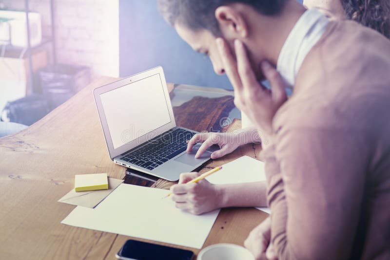 Commerciële vergadering in bureau, jonge ondernemer die, gebruikend laptop en lege bladen aan houten lijst samenwerken stock afbeeldingen Commerciële vergadering in bureau, jonge ondernemer die, gebruikend laptop en lege bladen aan houten lijst samenwerken stock afbeeldingen