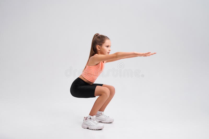 Commit to be fit. Flexible cute little girl child looking aside while doing sit ups isolated on a white background