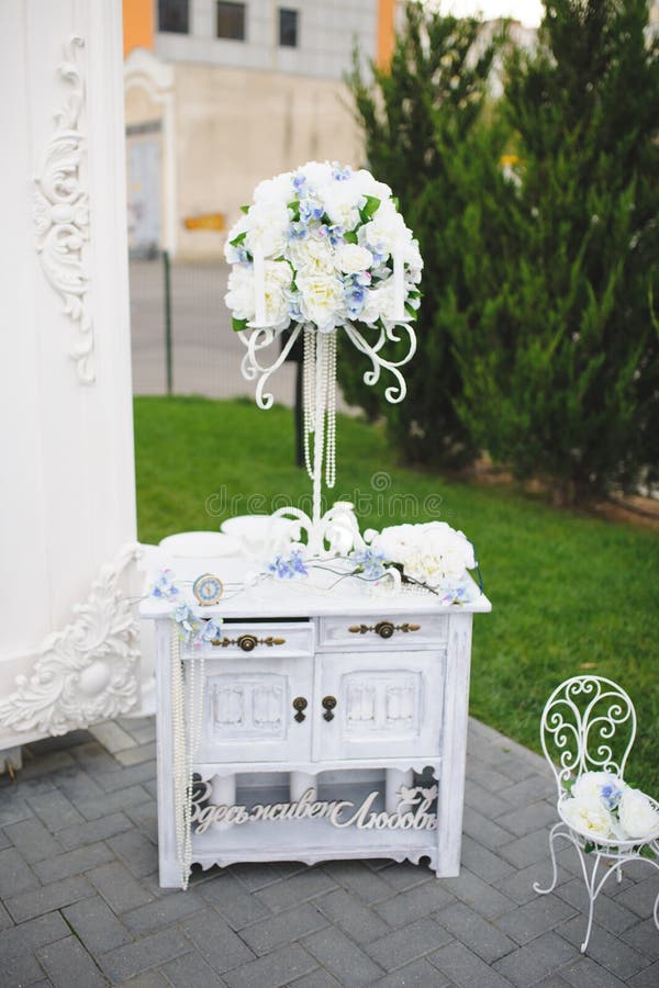 Decorated white commode with flower bouquet on stand. Decorated white commode with flower bouquet on stand