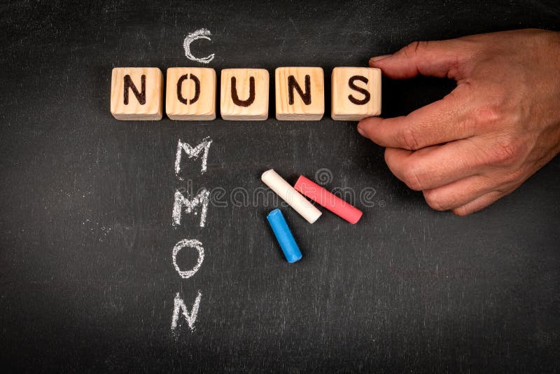 COMMON NOUNS Wooden Block Crossword Puzzle and Pieces of Chalk on a COMMON NOUNS Wooden Block Crossword Puzzle and Pieces of Chalk on a