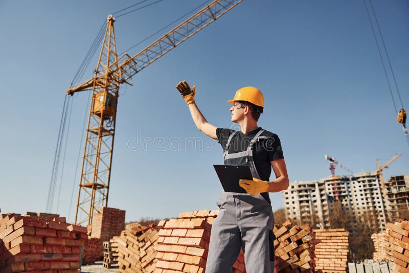 Communicating with Crane Guy. Construction Worker in Uniform and Safety Equipment Have Job on