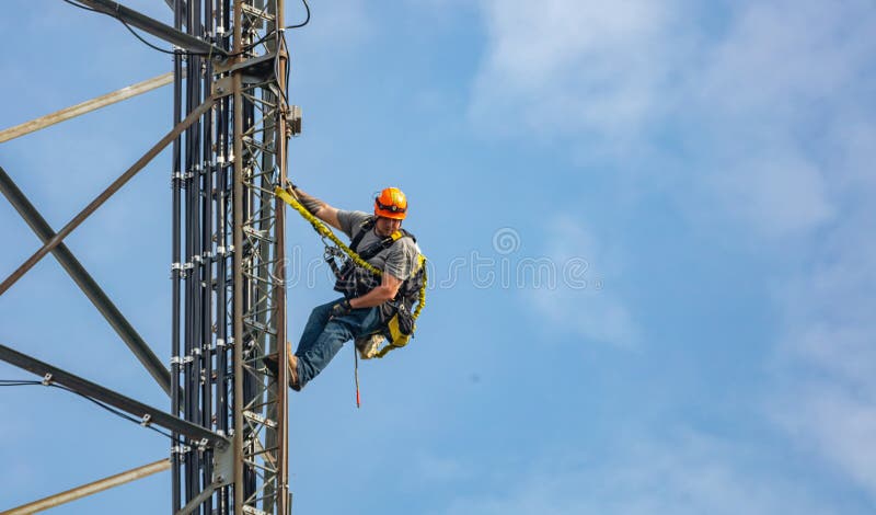 Communication maintenance. Technician climbing on telecom tower against blue sky background