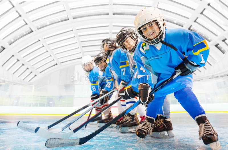 Compagni di squadra dell'hockey che stanno nella linea sulla pista di pattinaggio sul ghiaccio fotografie stock Compagni di squadra dell'hockey che stanno nella linea sulla pista di pattinaggio sul ghiaccio fotografie stock