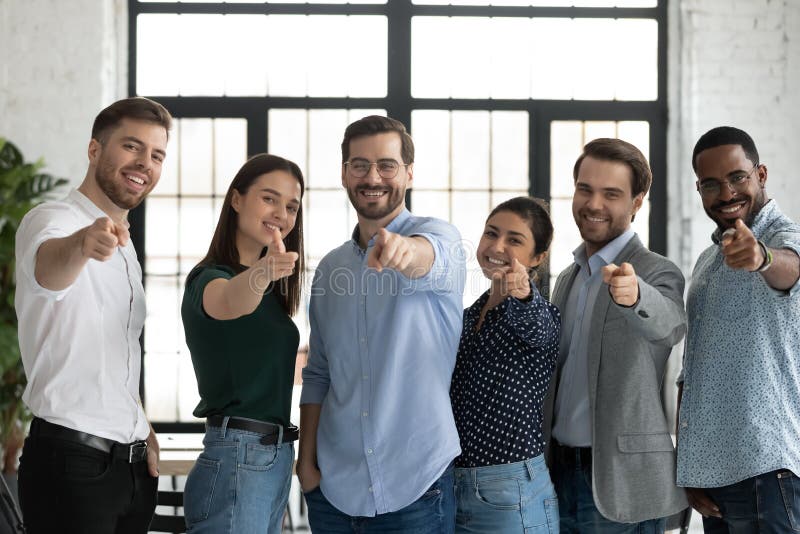 Compagni di squadra multietnici che puntano le dita verso le telecamere scegliendo un nuovo collega fotografie stock