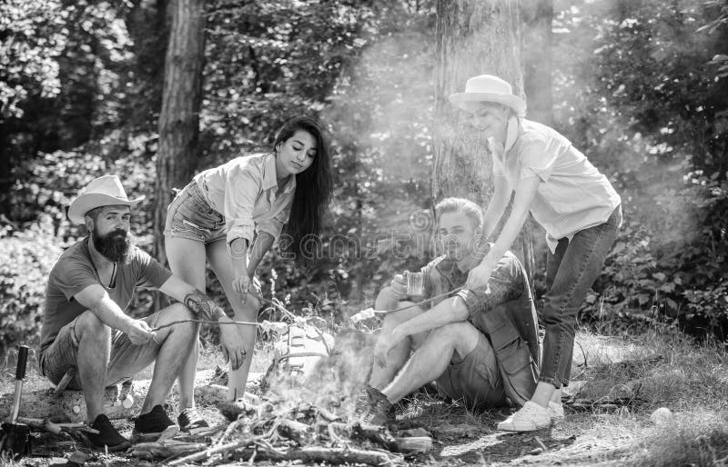 Company friends or family picnic roasting food. Plan for perfect day hike picnic. Friends relaxing near bonfire royalty free stock images Company friends or family picnic roasting food. Plan for perfect day hike picnic. Friends relaxing near bonfire royalty free stock images