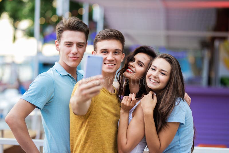 A company of good-looking friends is laughing and making selfie in the nice summer cafe. Entertainment, having good time royalty free stock photo A company of good-looking friends is laughing and making selfie in the nice summer cafe. Entertainment, having good time royalty free stock photo