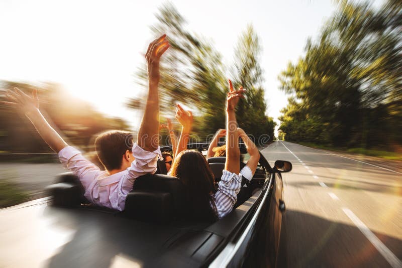 Company of young people riding in a cabriolet on the road and ho royalty free stock photo Company of young people riding in a cabriolet on the road and ho royalty free stock photo