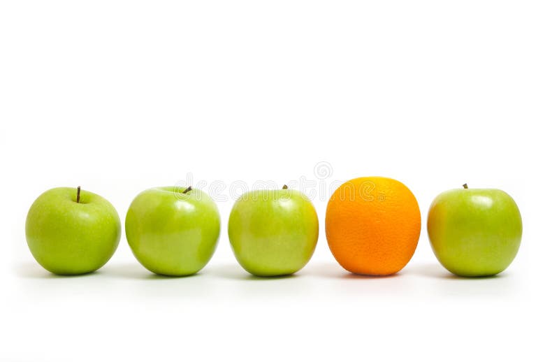 Green apples lined up with one orange on a white background. Green apples lined up with one orange on a white background