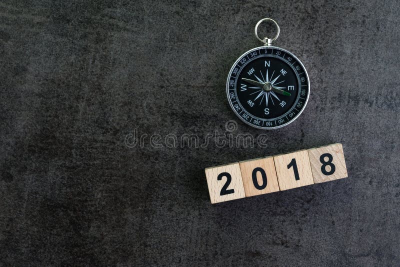 Compass and wooden block number 2018 on dark black background as