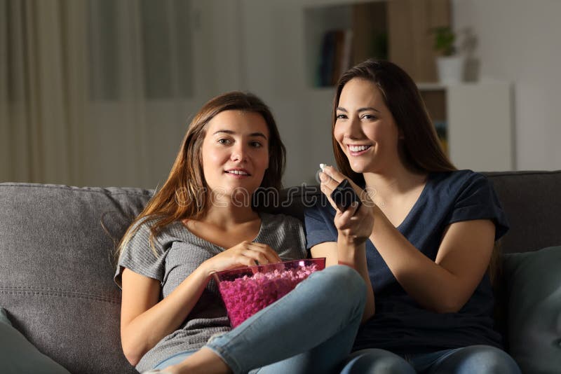 Compañeros de cuarto felices wathing la TV en la noche imágenes de archivo libres de regalías Compañeros de cuarto felices wathing la TV en la noche imágenes de archivo libres de regalías