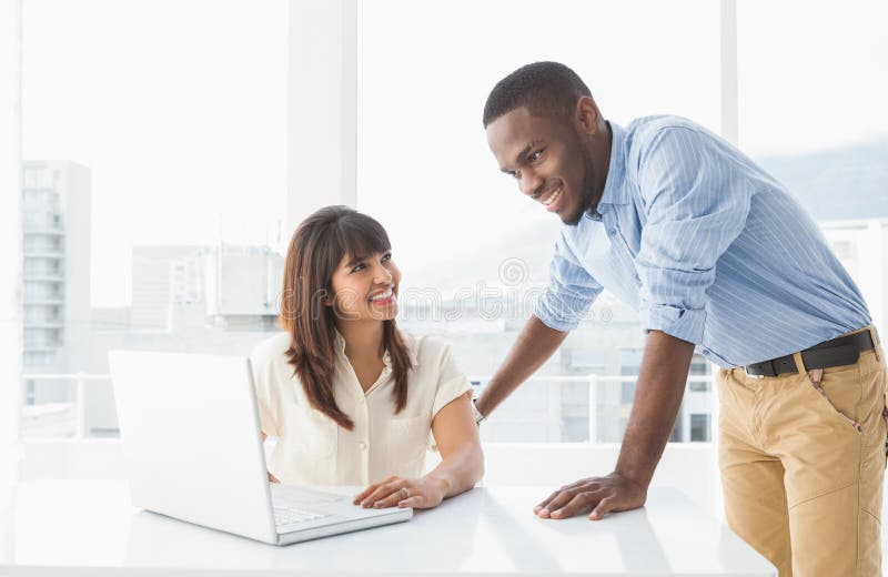 Compañeros De Trabajo Sonrientes Que Hablan Y Que Usan El Ordenador Portátil Que Se Sienta En El