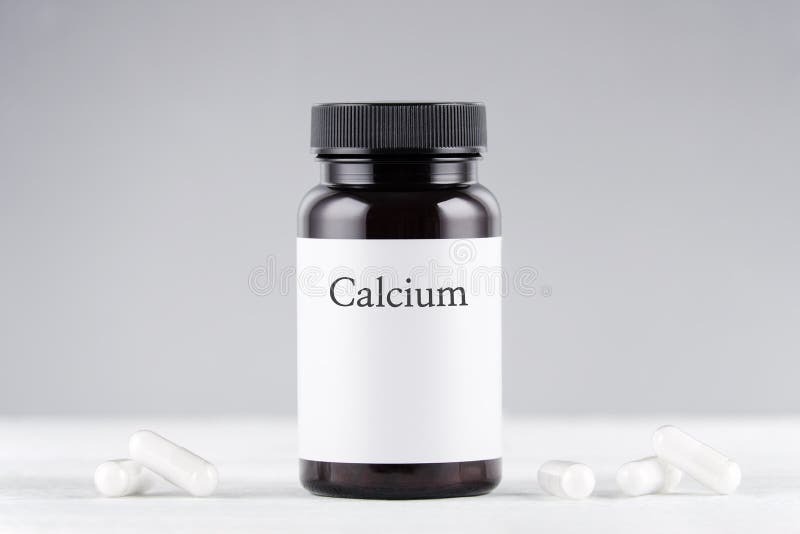 Nutritional supplement calcium bottle and capsules on gray background. Nutritional supplement calcium bottle and capsules on gray background