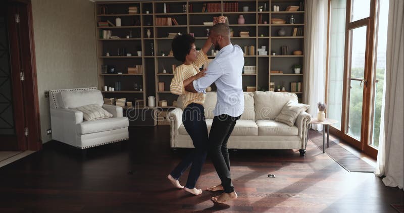 Complet heureux couple africain dansant pieds nus dans le salon banque de vidéos