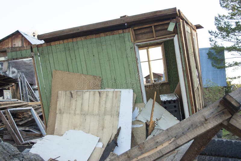 Completely ruined house, broken windows. Garbage, tires, wooden boards, pieces of plywood stock image Completely ruined house, broken windows. Garbage, tires, wooden boards, pieces of plywood stock image