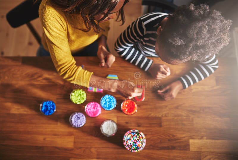 Completi giù il punto di vista dell'adulto e del bambino che scelgono le perle fotografia stock Completi giù il punto di vista dell'adulto e del bambino che scelgono le perle fotografia stock