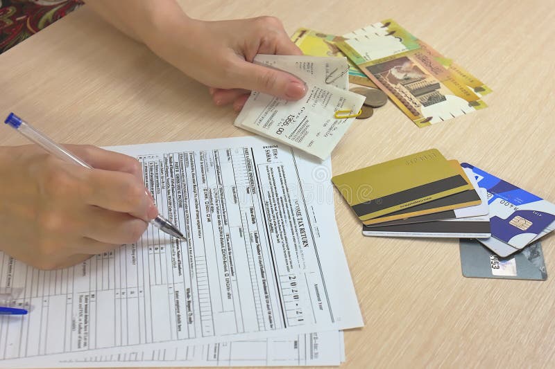 Completing tax form. Hand with pen over tax form on the background of money and credit cards. royalty free stock photos Completing tax form. Hand with pen over tax form on the background of money and credit cards. royalty free stock photos