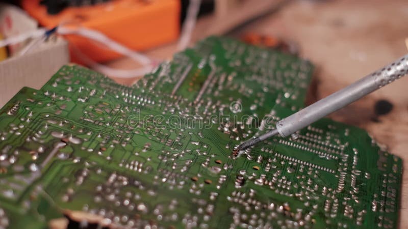 Composants électroniques à souder à la main par un technicien sur circuit imprimé vert banque de vidéos