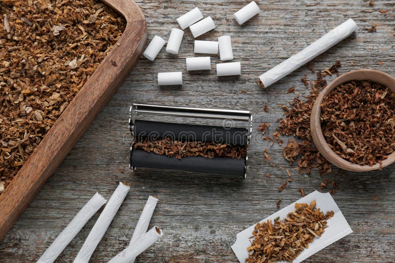 Flat lay composition with roller and tobacco on old table. Making hand rolled cigarettes. Flat lay composition with roller and tobacco on old table. Making hand rolled cigarettes