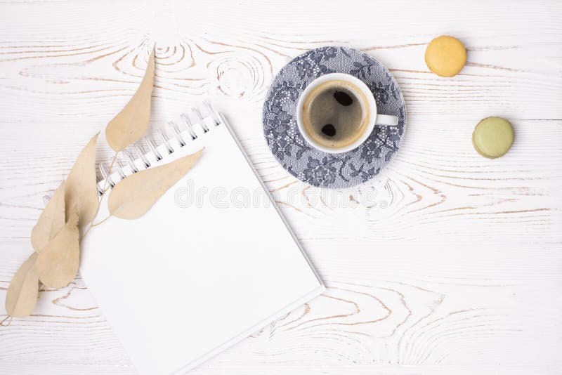 Composición de un diario vacío con un resorte, una taza de café y macarons y hojas beige sobre una mesa blanca de madera oscura imagenes de archivo Composición de un diario vacío con un resorte, una taza de café y macarons y hojas beige sobre una mesa blanca de madera oscura imagenes de archivo