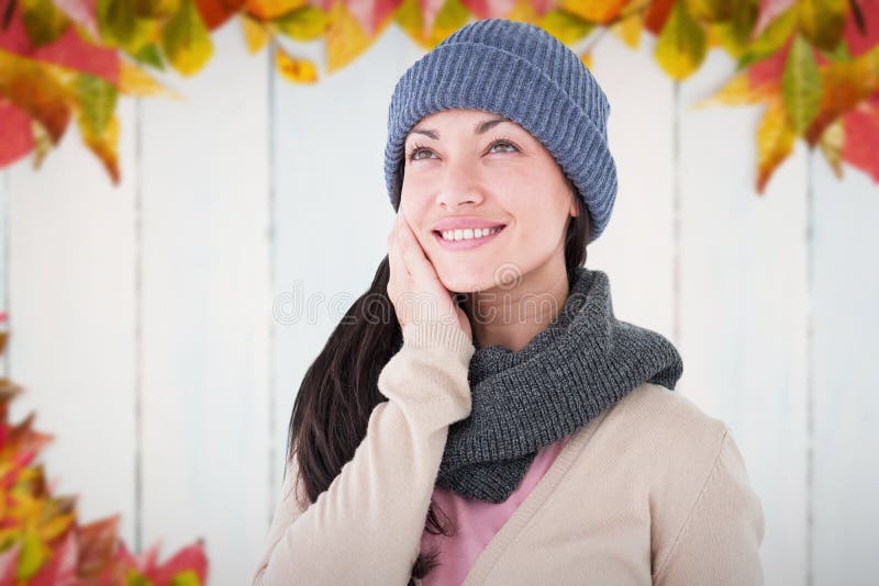 Attractive brunette looking up wearing warm clothes against autumn leaves on wood. Attractive brunette looking up wearing warm clothes against autumn leaves on wood