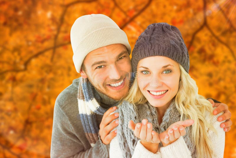 Composite image of attractive couple in winter fashion smiling at camera royalty free stock images Composite image of attractive couple in winter fashion smiling at camera royalty free stock images