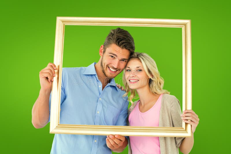 Composite image of attractive young couple holding picture frame