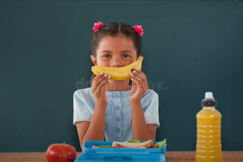 Composite image of girl holding banana at table