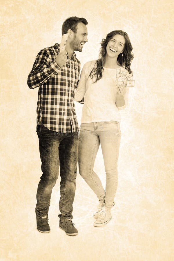 Grey background against happy young couple holding fanned out currency notes. Grey background against happy young couple holding fanned out currency notes