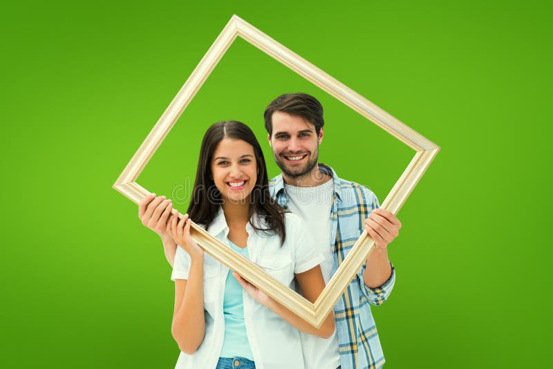 Composite image of happy young couple holding picture frame