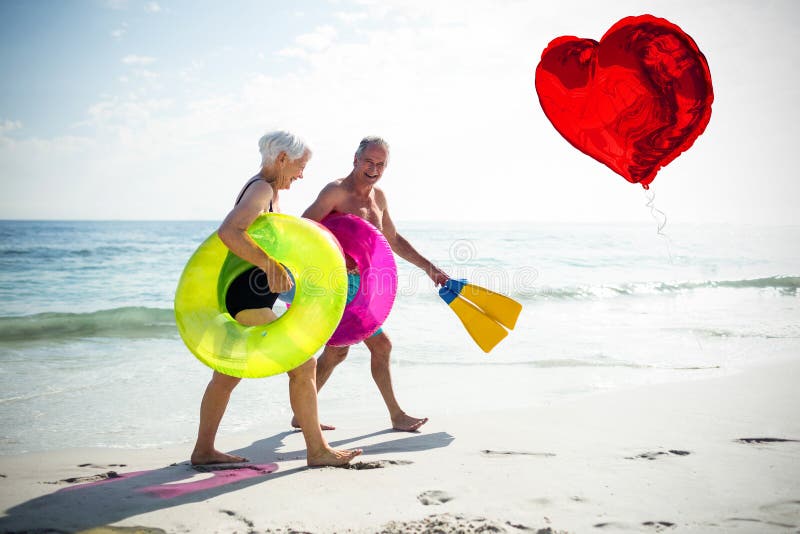 Composite image of senior couple on beach and red heart balloon 3d